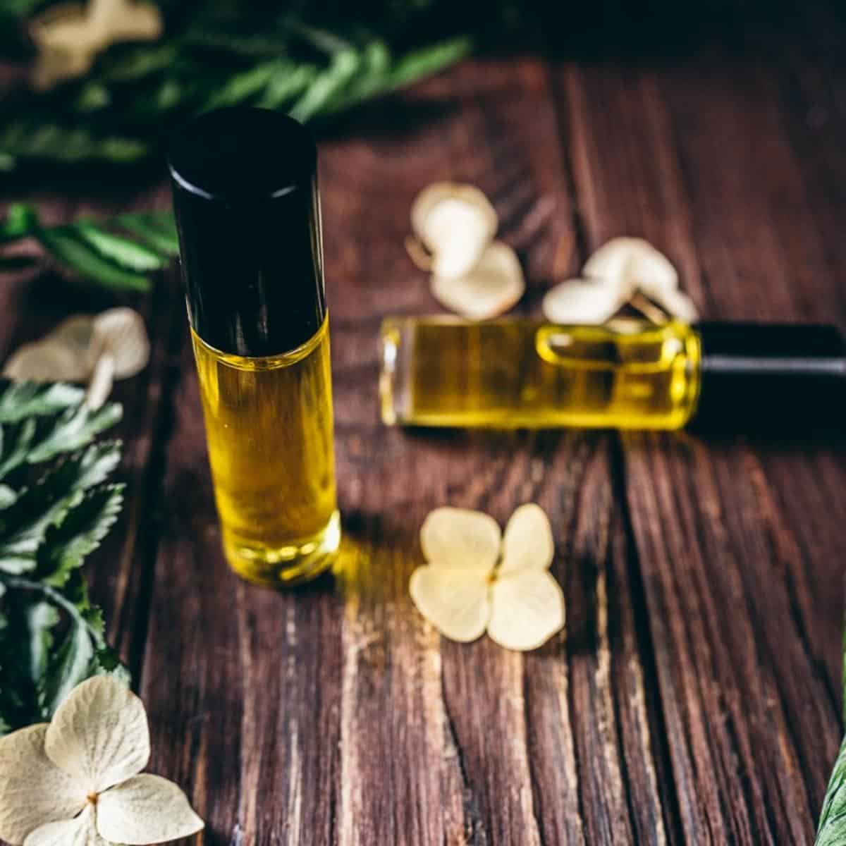 A roller bottle filled with yellow oil standing on a dark wooden tabletop.