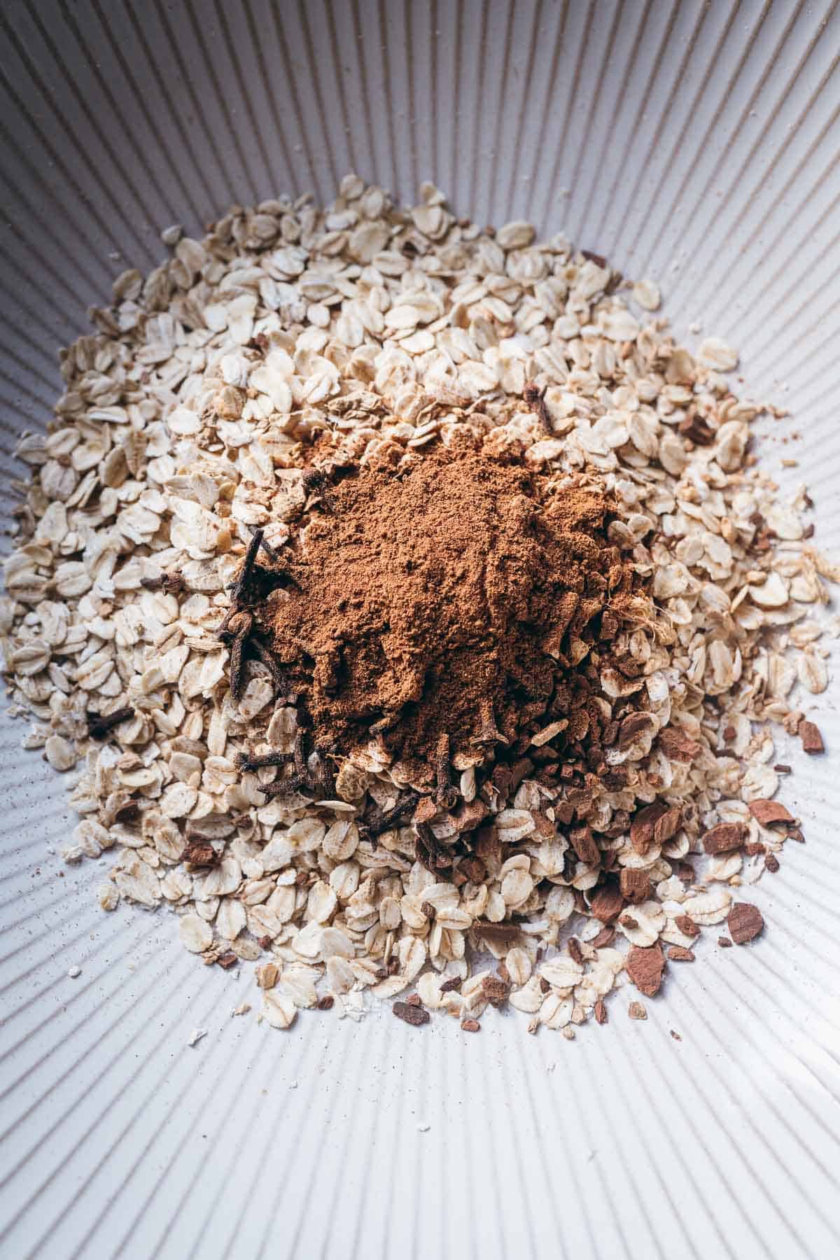 A close shot of oats and spices resting in a white ceramic bowl.