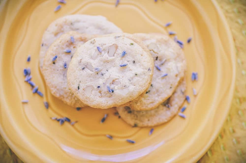 A yellow plate topped with white cookies dusted with small lavender flowers.