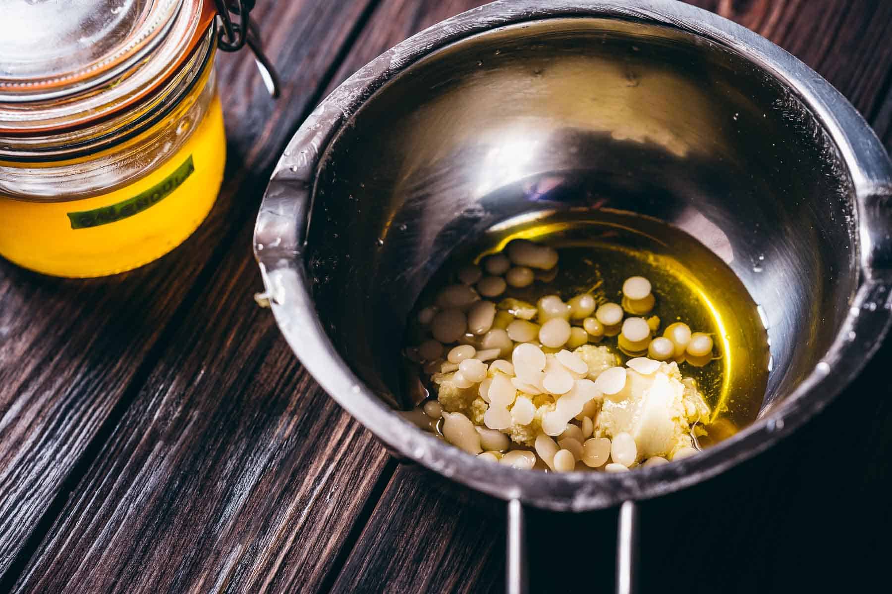 A double boiler filled with oil and beeswax pellets.