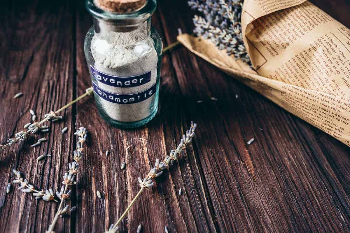 A clear jar filled with a gray sand-like substance with a cork stuck in the top.