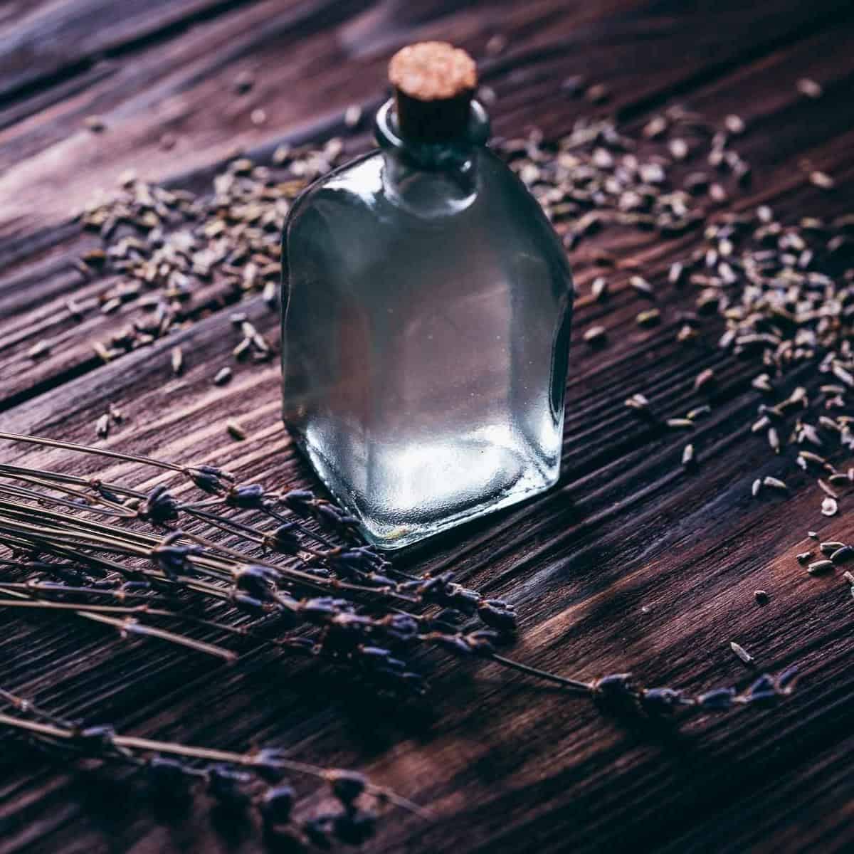 A clear glass bottle with a cork rests on a dark tabletop.