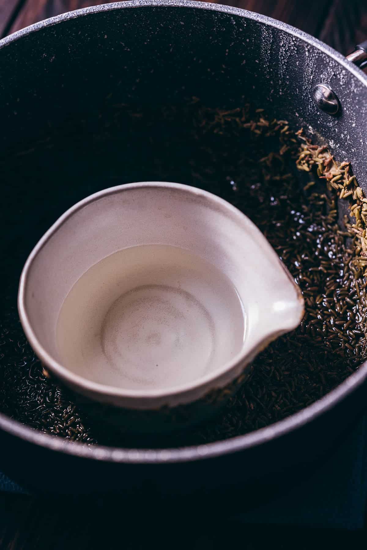 Lavender water resting in the center of a ceramic bowl sitting in the center of a large pot.