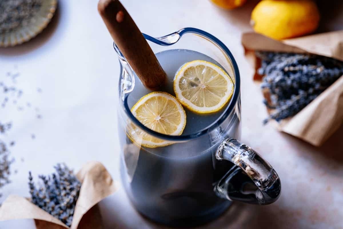 A large clear glass picture filled with a lavender colored liquid with lemon slices floating on top.