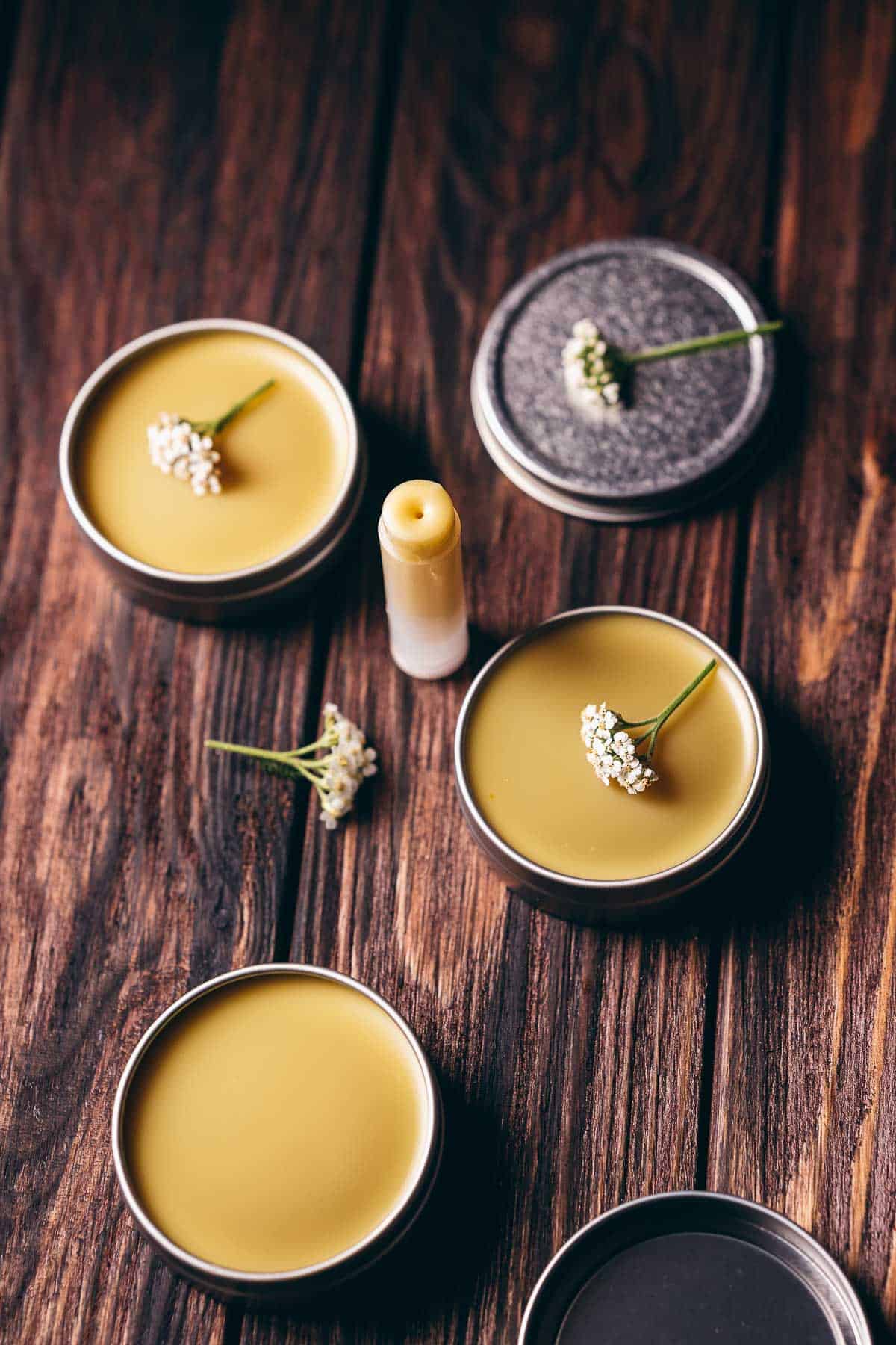 Silver balm tin and a lip balm tub filled with a yellow balm.