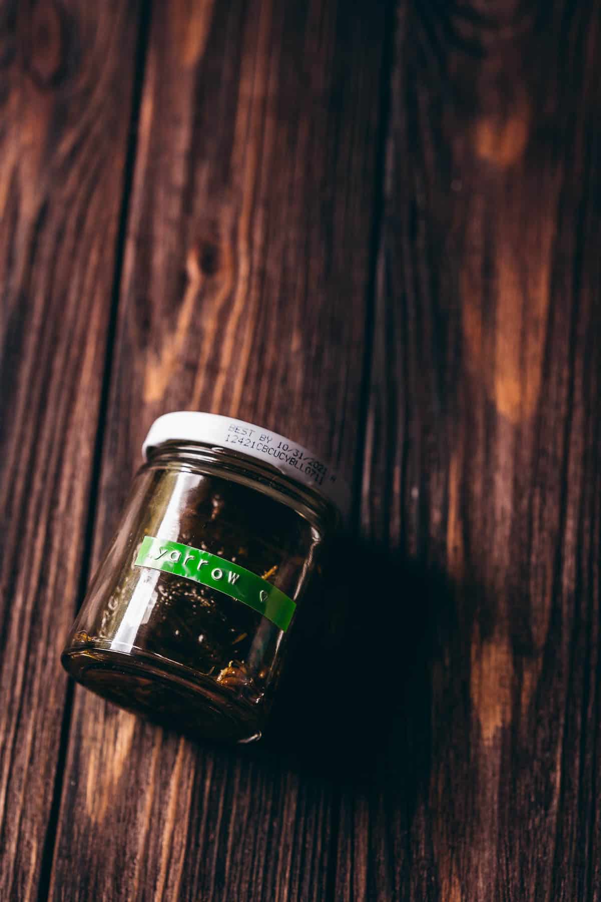 A clear glass jar with a green label that says yarrow.