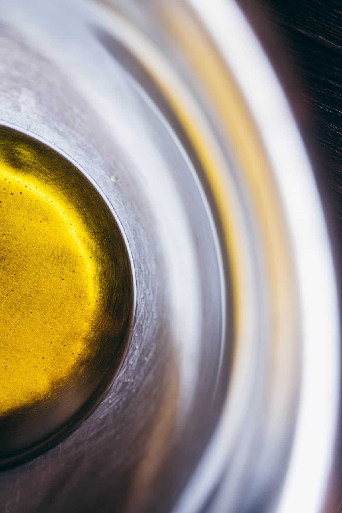 A silver mixing bowl filled with yellow oil.