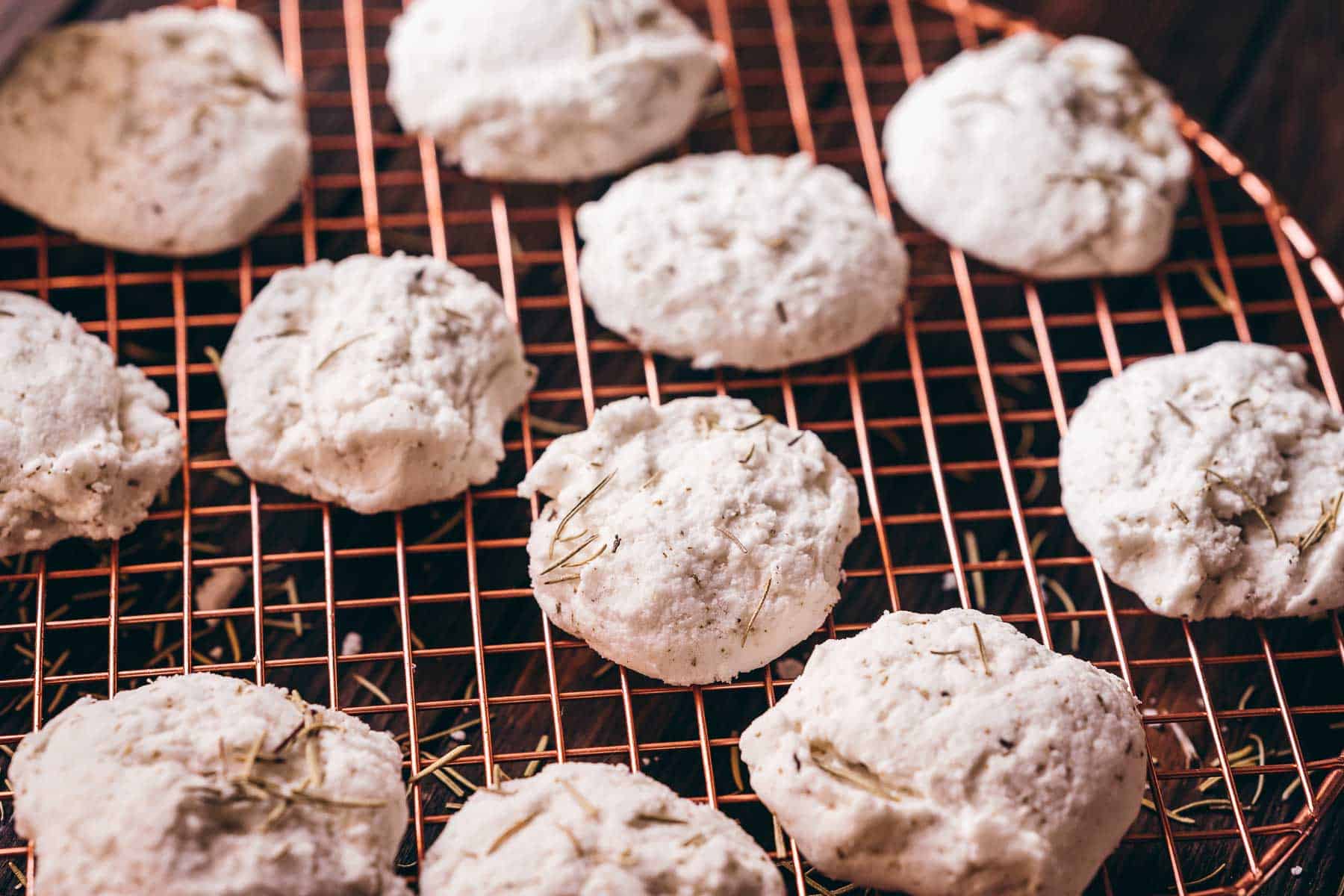 Homemade white bath truffles resting on a bronze colored drying rack.