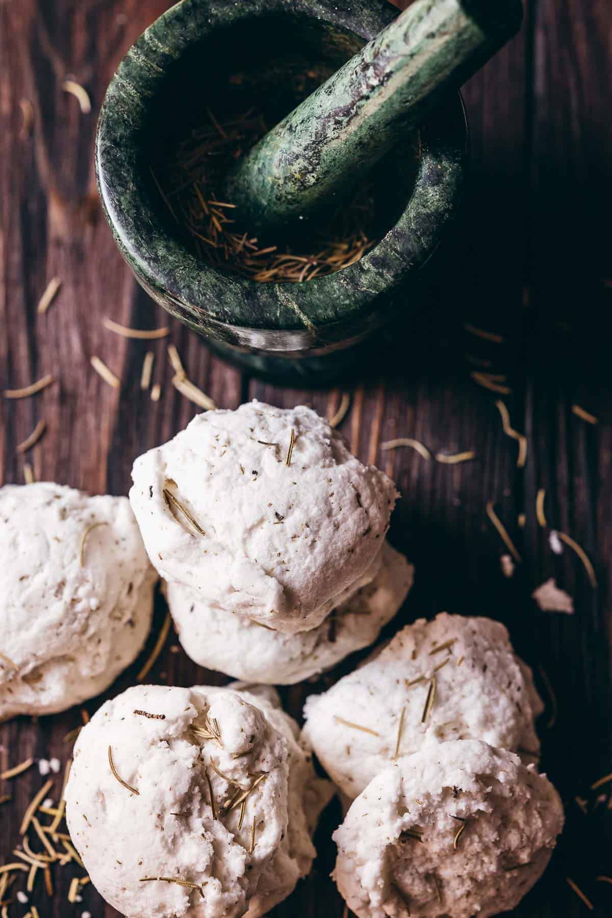 A dark green mortar and pestle rests next to a pile of homemade bath truffles.