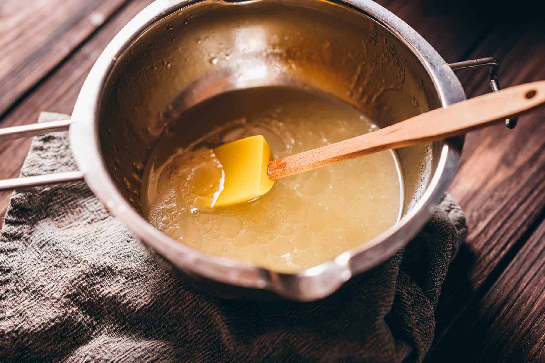 A silver double boiler pot filled with yellow liquid.