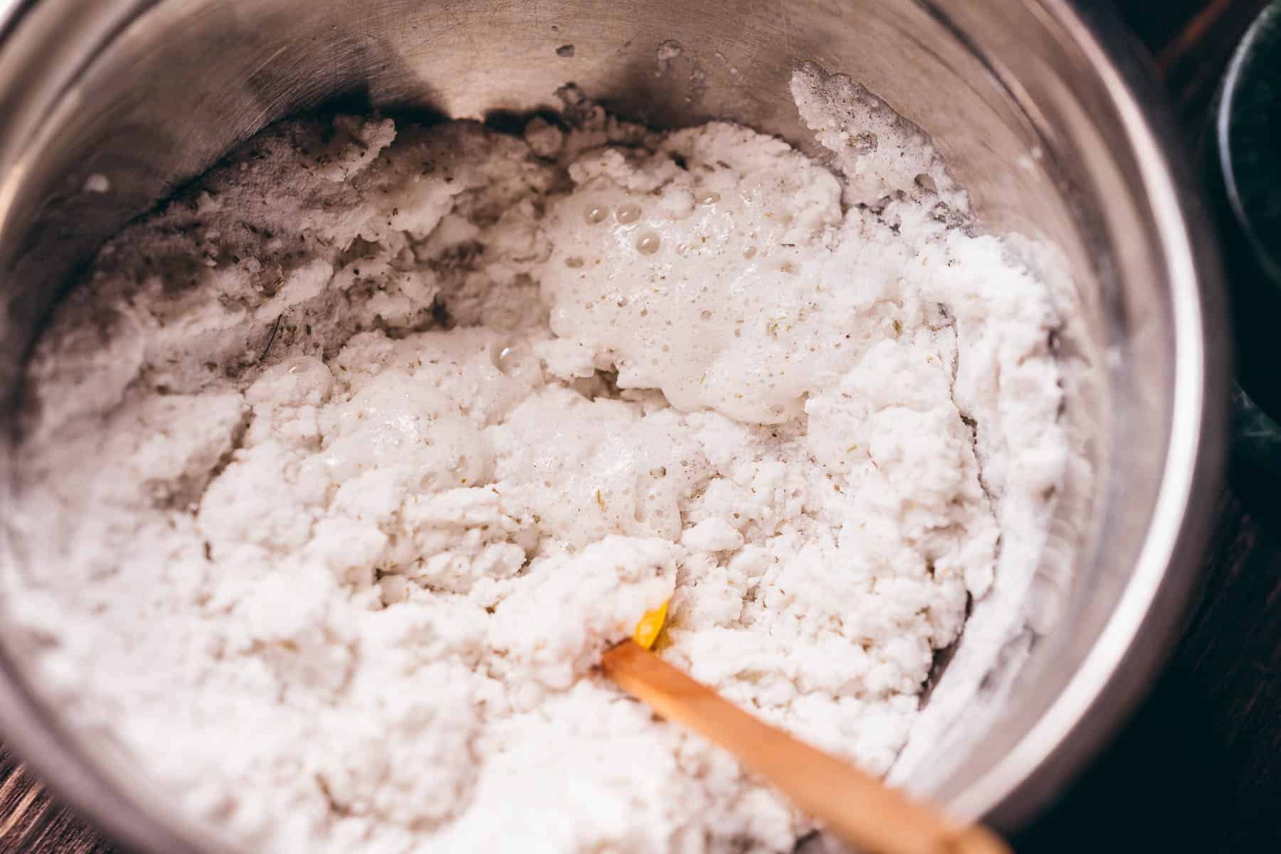 A silver mixing bowl filled with a white wet powder.