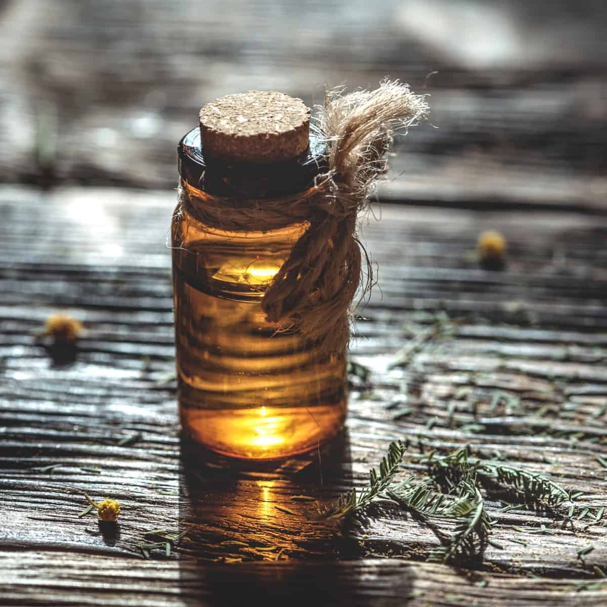 A small clear glass of essential oil resting on a wooden table.