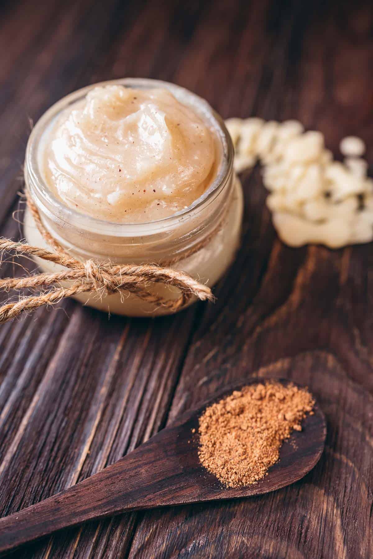 A small jar of white lotion on a dark table.