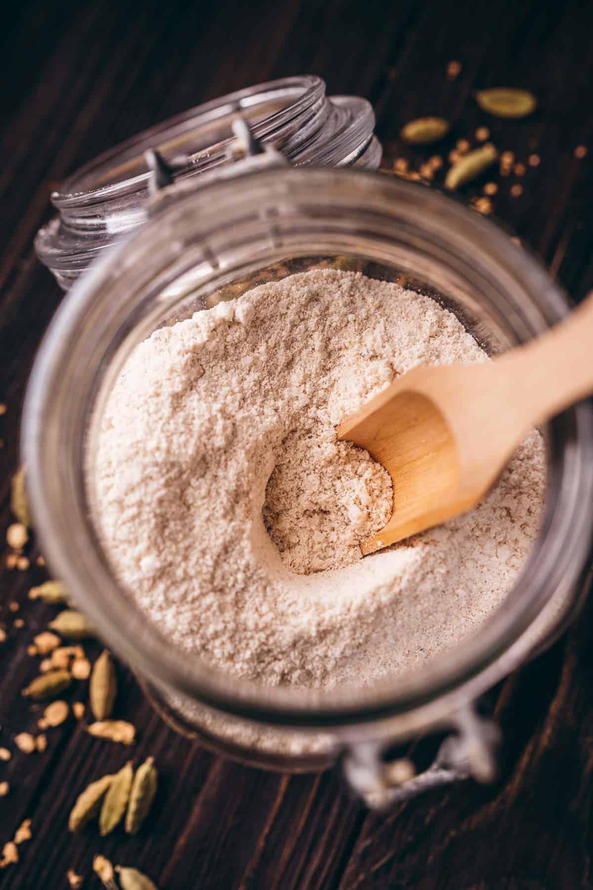 Pistachio flour in a jar with a wooden spoon and coconut milk bath.