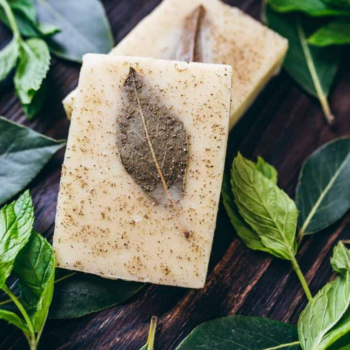 A DIY shampoo bar with mint leaves on a wooden table.