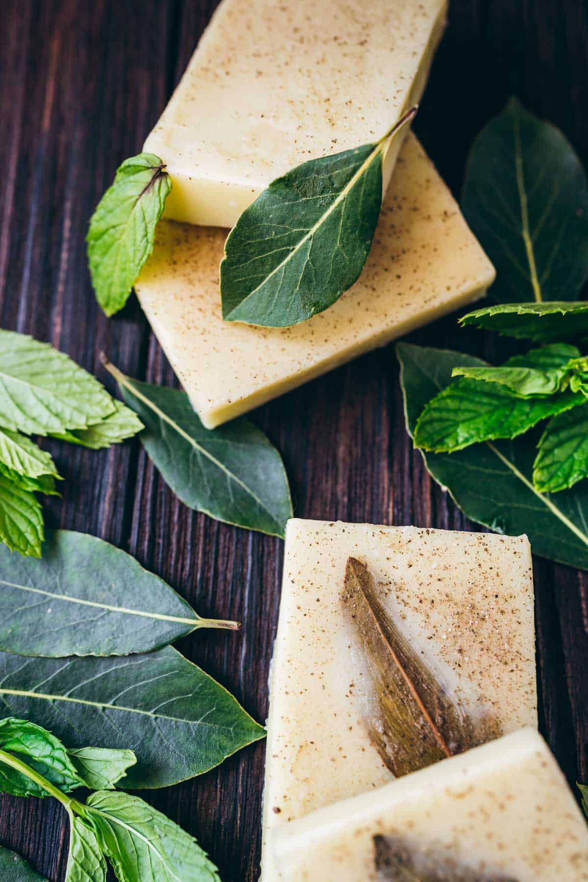 Soap bars with sage and mint leaves on a wooden table, perfect for DIY shampoo bars.