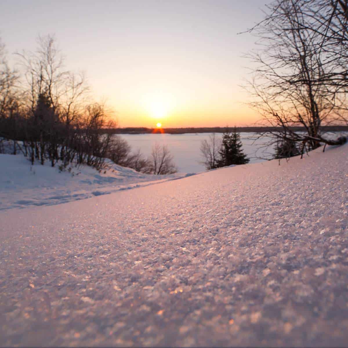 The sun is setting over a winter landscape.