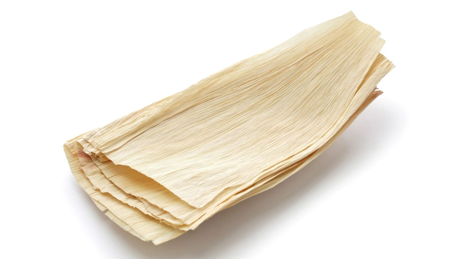 A stack of dried corn husks arranged in a pile on a white background.