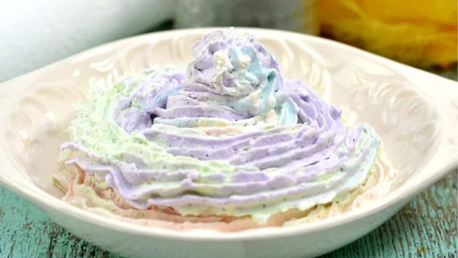 A bowl filled with pastel-colored whipped cream swirled in light purple, green, blue, and pink tones.