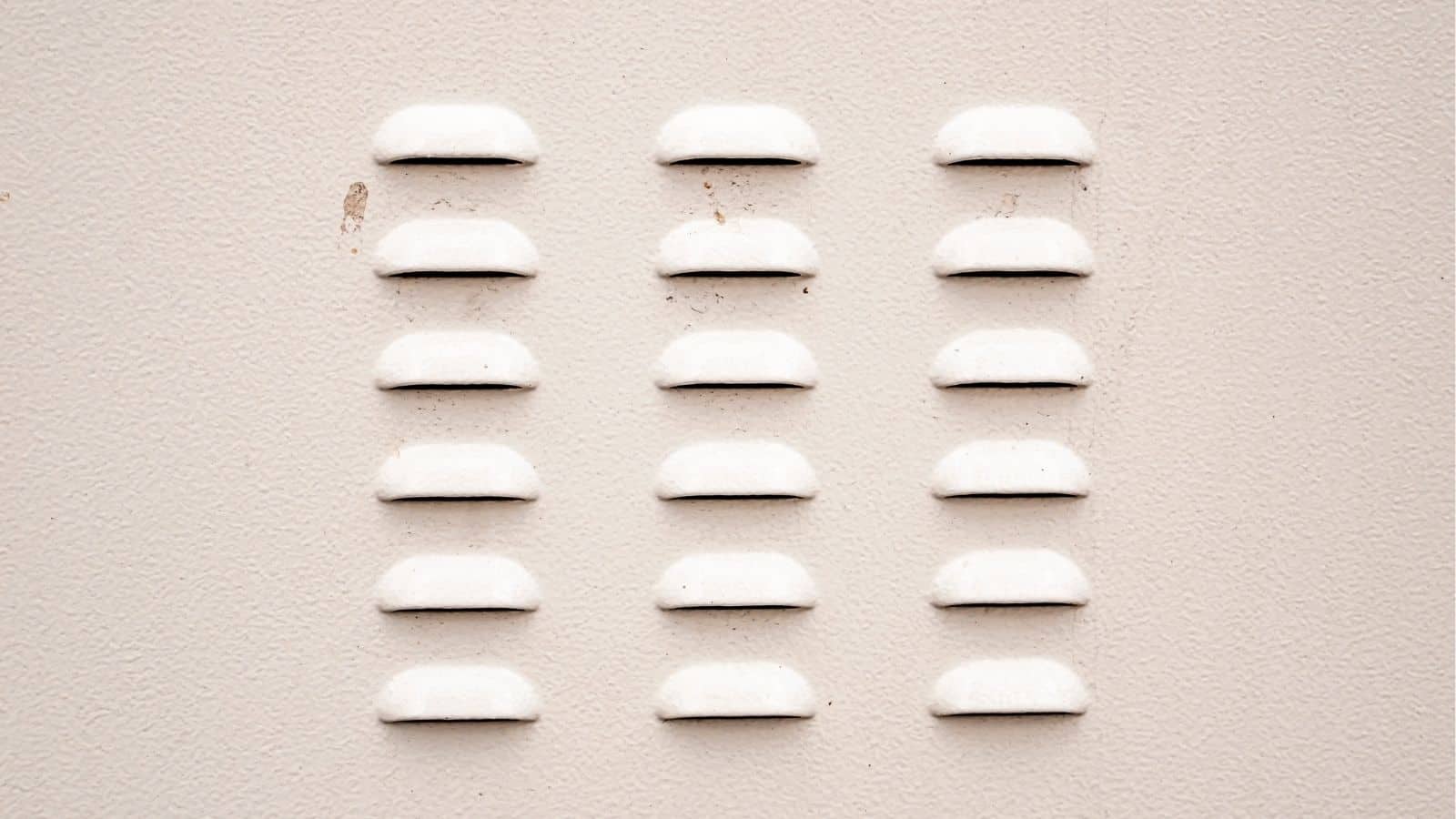 Fifteen small, white, half-circle bumps arranged in a 3 by 5 grid on a textured, off-white surface.