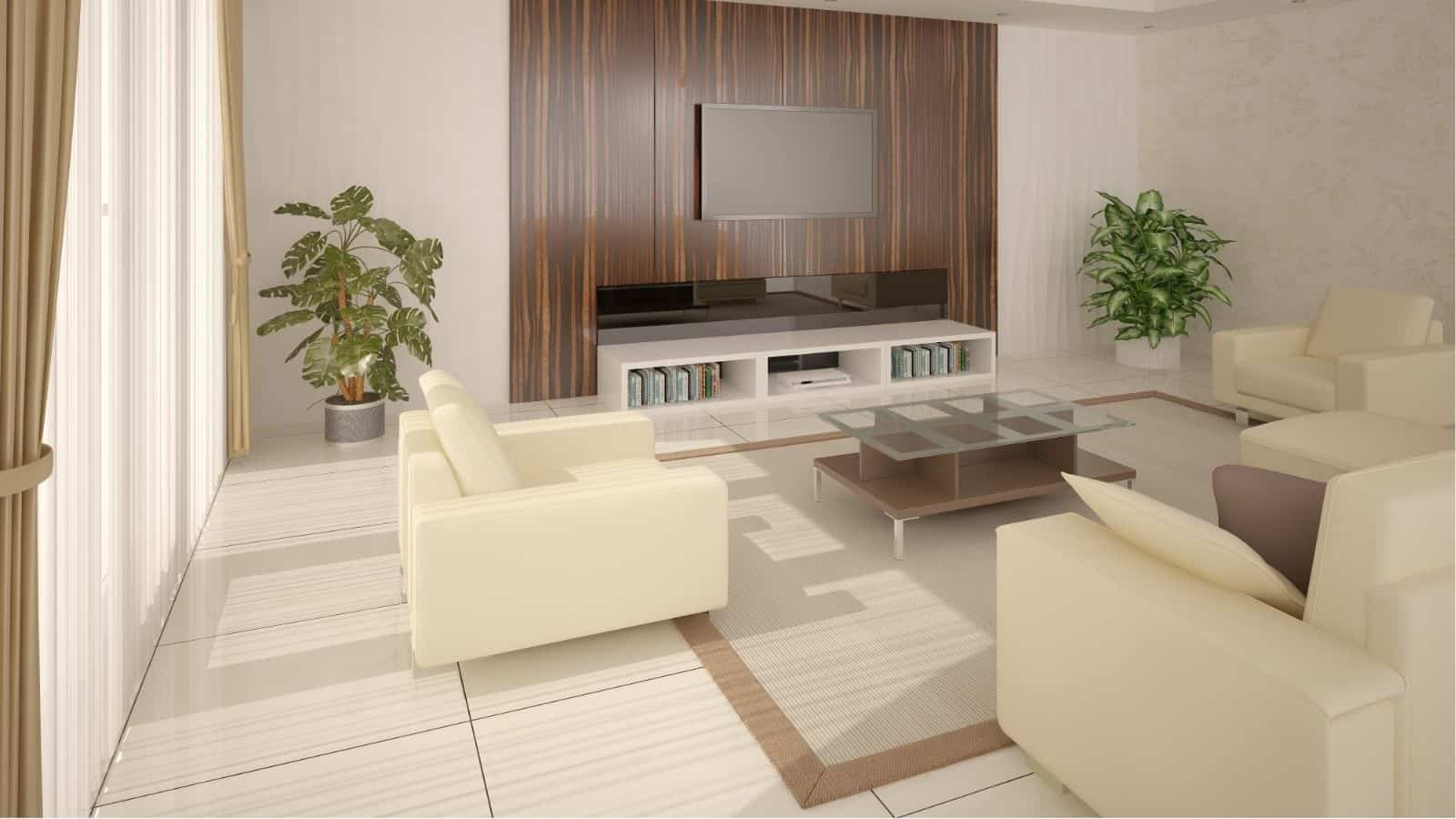 Modern living room with cream armchairs, glass coffee table, TV mounted on a wood accent wall, built-in shelves, houseplants, and large windows with curtains.