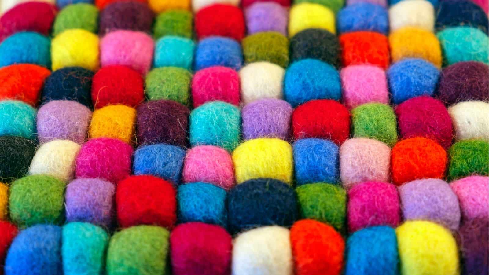 Rows of small, colorful felt balls arranged closely together in a grid pattern.