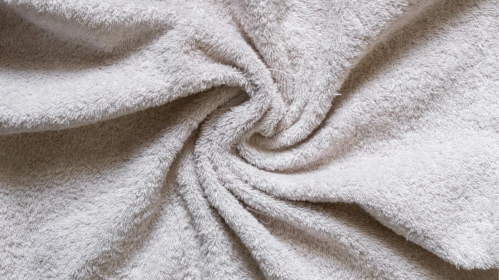 A close-up view of a light gray towel with a spiral twist pattern in the fabric, showing its soft and textured surface.