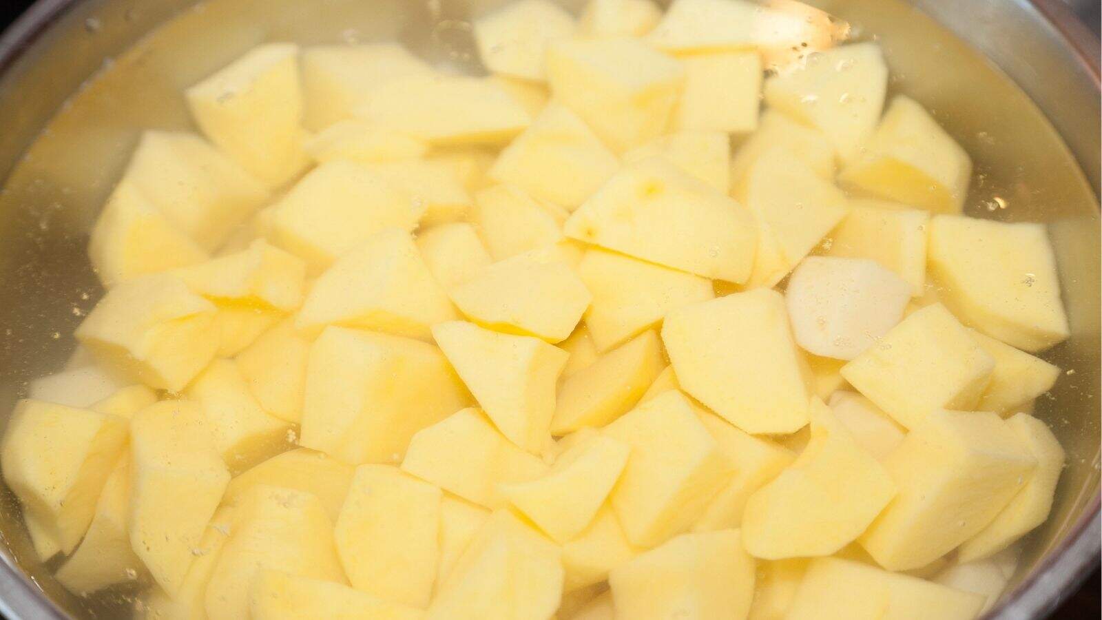 Cubed raw potatoes are soaking in a bowl of water.